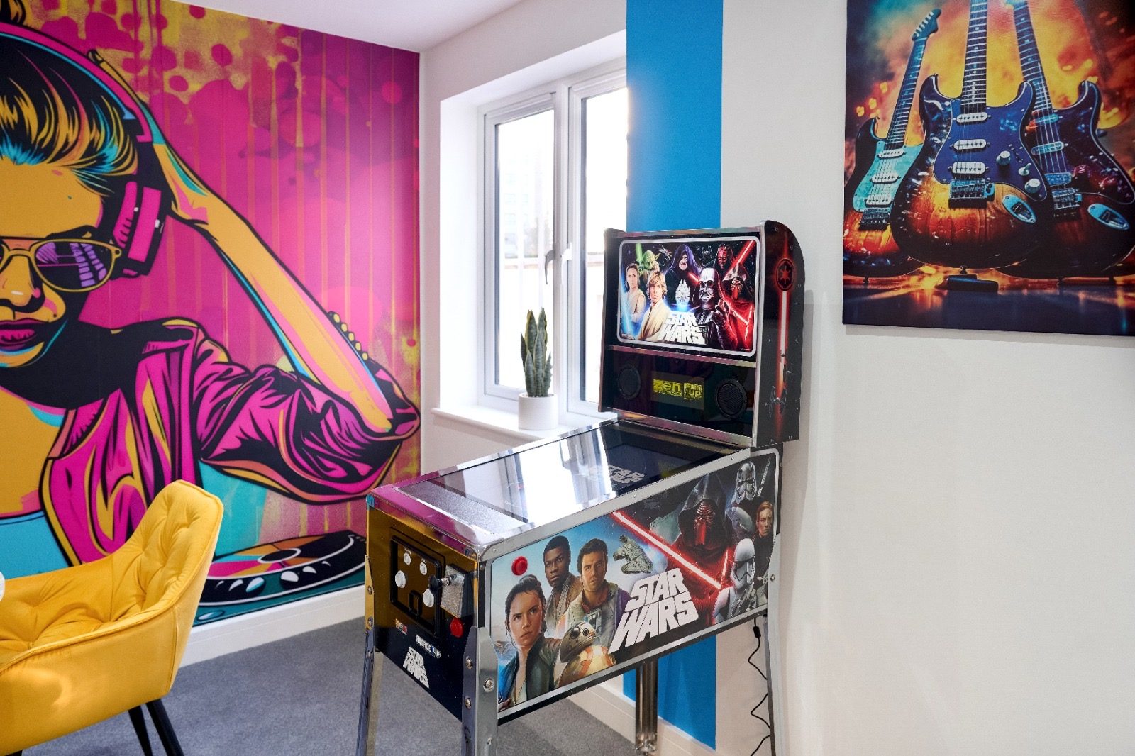 Games lounge with pinball machine and hand-painted DJ mural