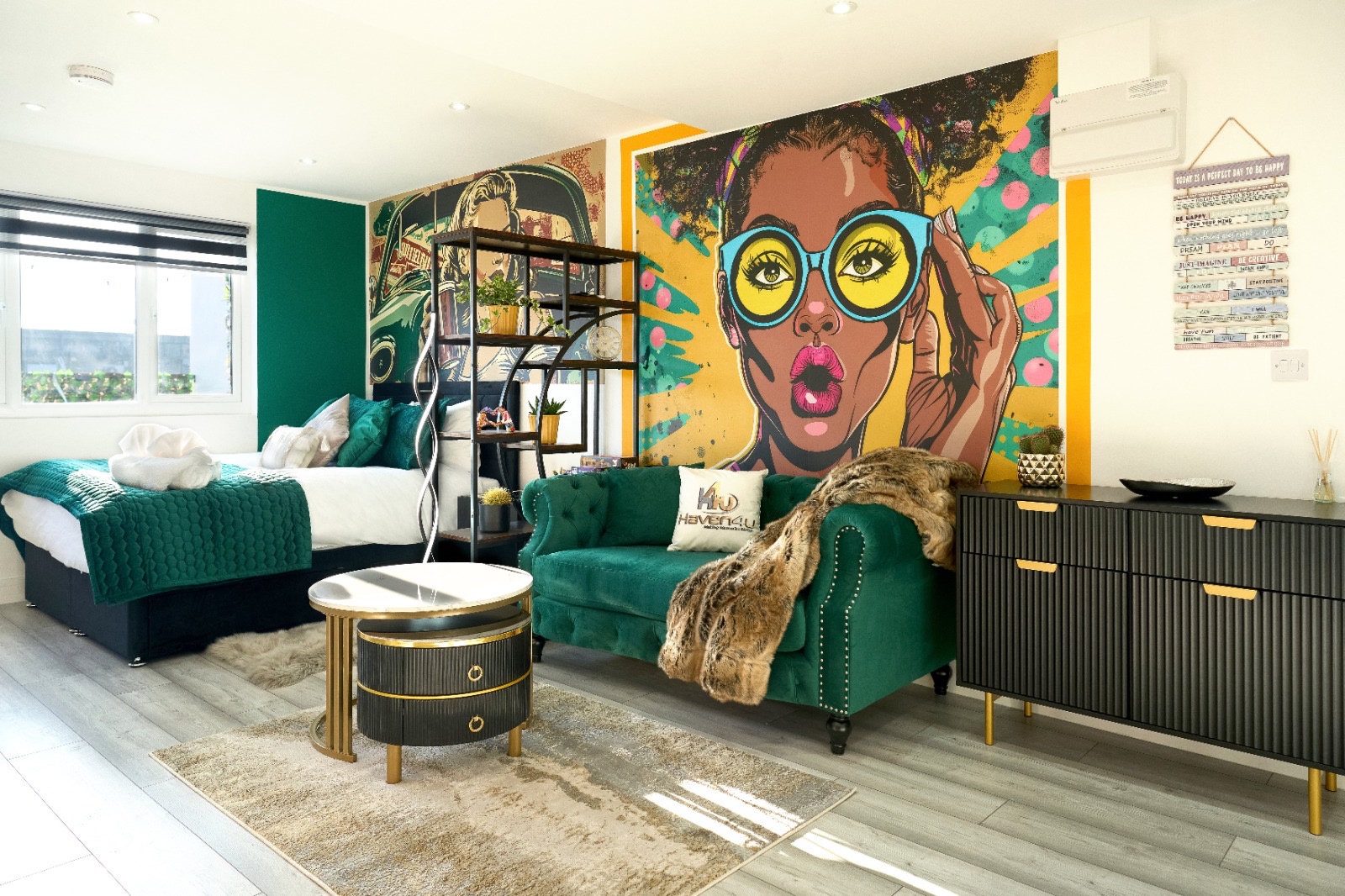 Open-plan room with beds, green sofa and pop-art mural