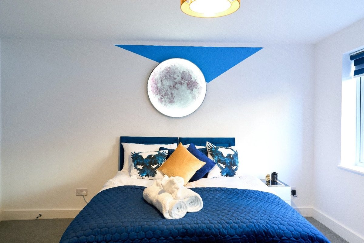 Double bed with navy bedding beneath a circular moon light