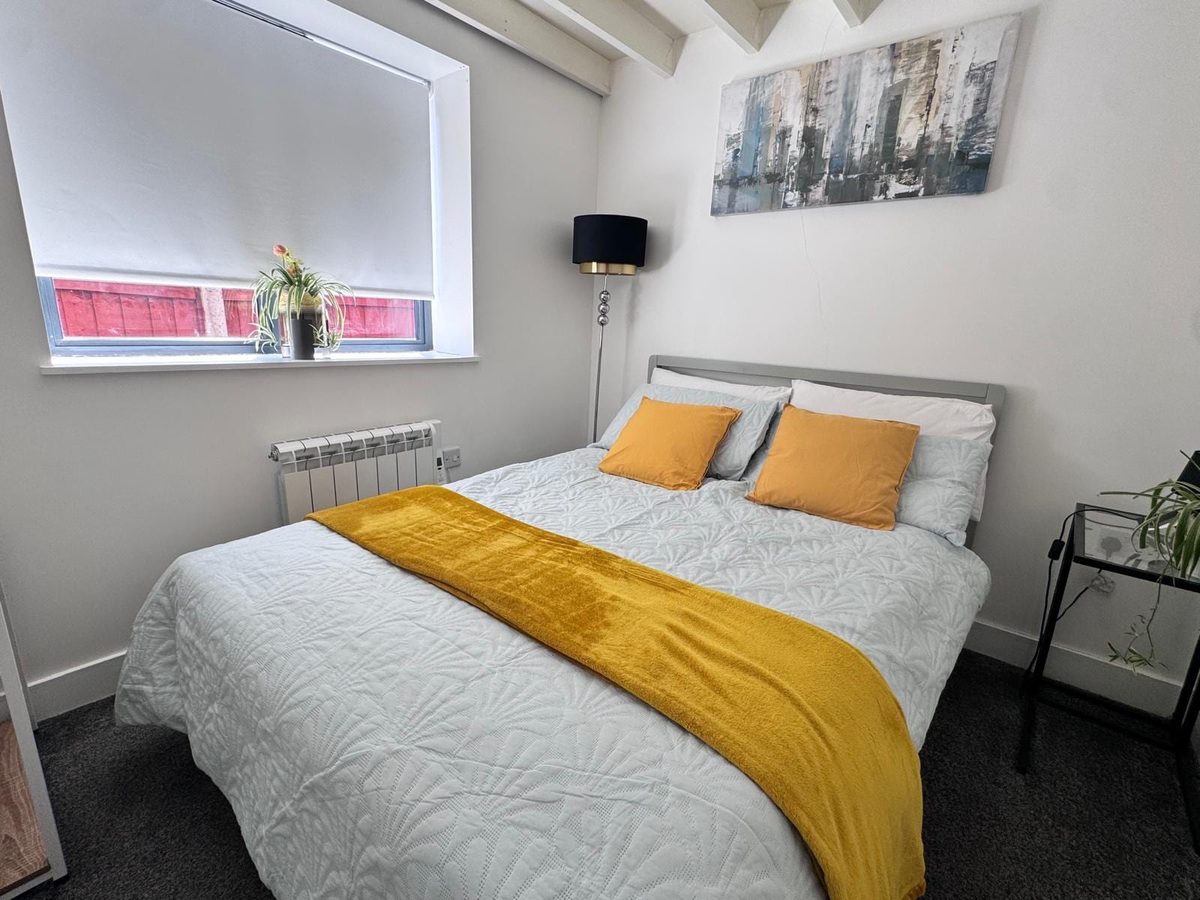 Double bed with grey bedding and a mustard throw
