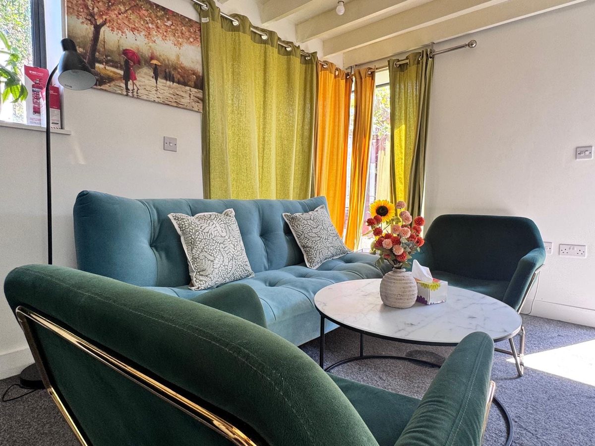 The Garden Studio living area with a teal velvet sofa and green armchairs