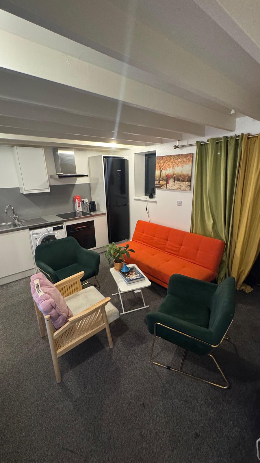 Fitted kitchen with oven, fridge freezer and orange sofa bed